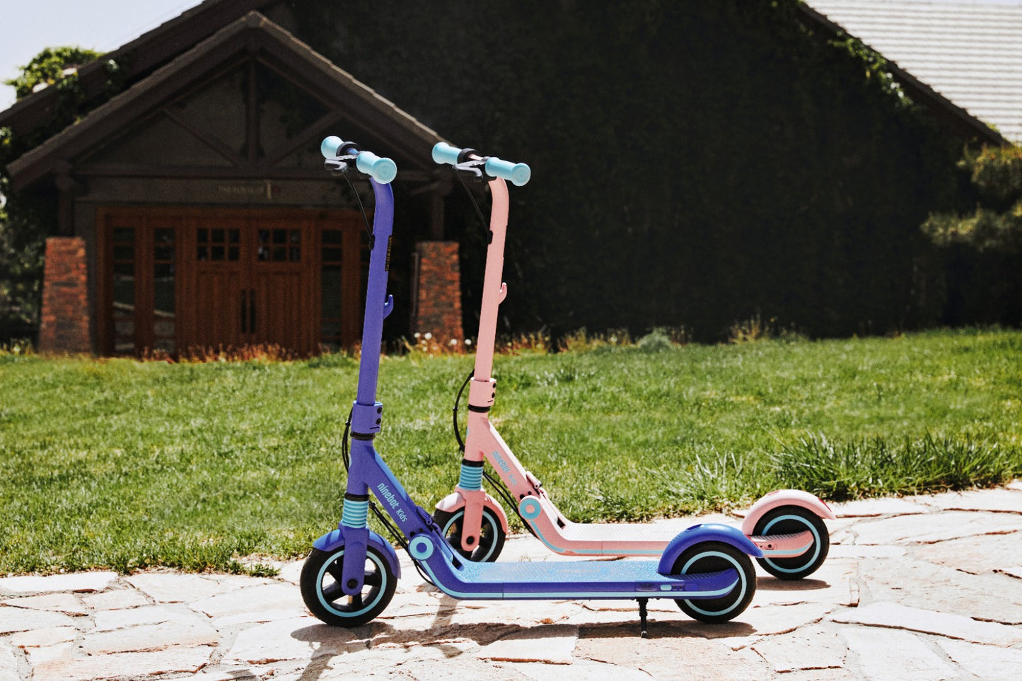 Segway Ninebot Zing E8 electric kickscooter for kids ages 6 to 12 years old. Comes in two colours blue and pink. Safe and easy to ride. Foldable and portable. Outside on the sidewalk on a sunny day.
